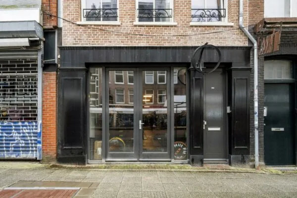 Voorgevel van een zwart winkelpand met grote glazen deuren aan de Albert Cuypstraat in Amsterdam.